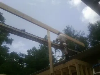 Carpenter setting a ridge beam over a new addition frame — Ice Dam Removal by Roofing Brothers in Rumney