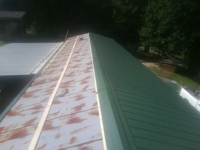 Old rusted panels beside newly installed green metal roofing — Wind Damage Roof Repair by Roofing Brothers in Rumney