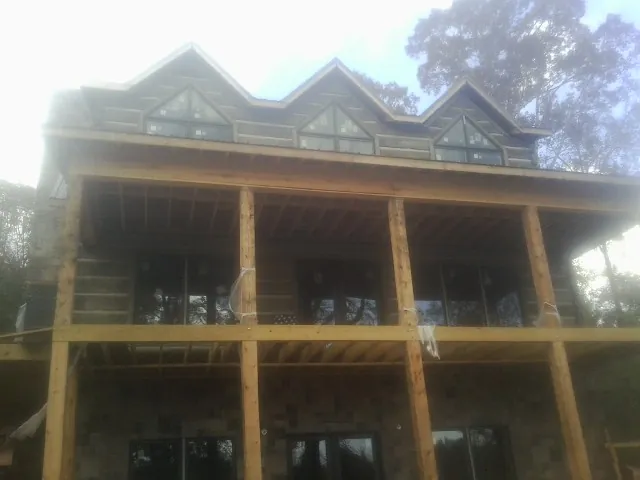 Dormers and porch framing on a large log home under construction — Roof Coating work by our crew in Rumney