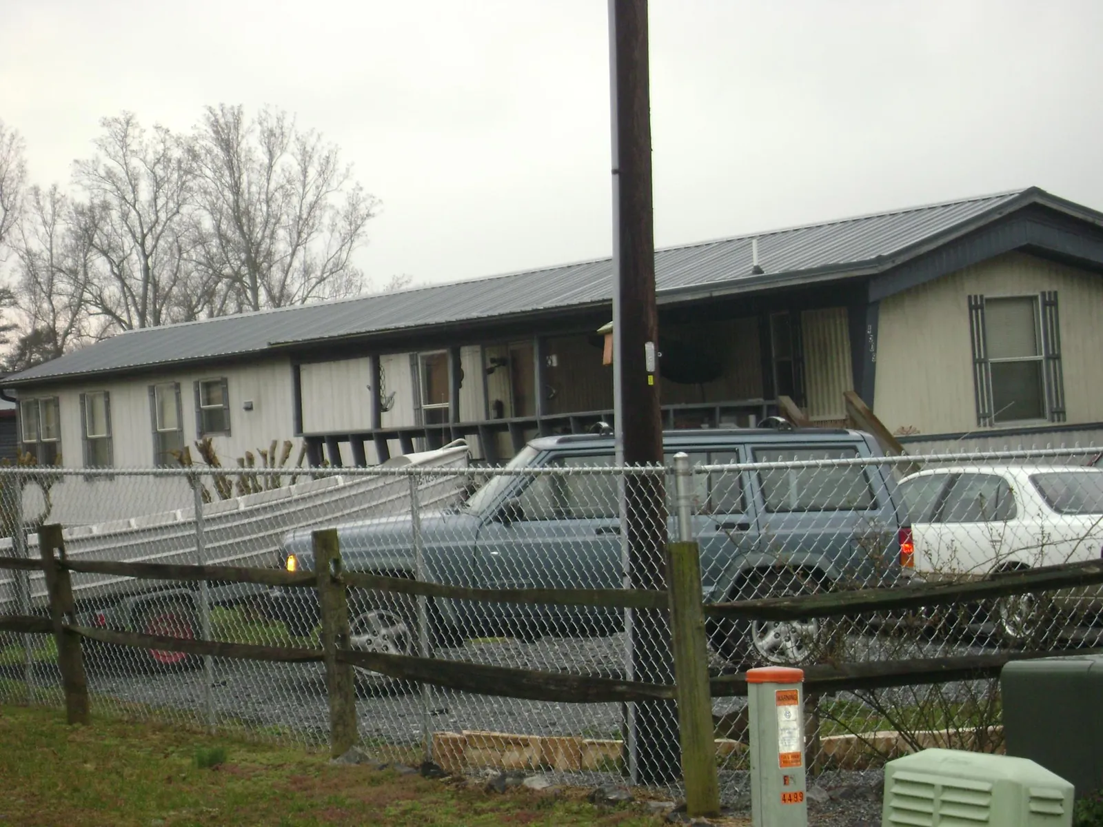 Dark metal roof on a long single story building behind a chain link fence in Rumney