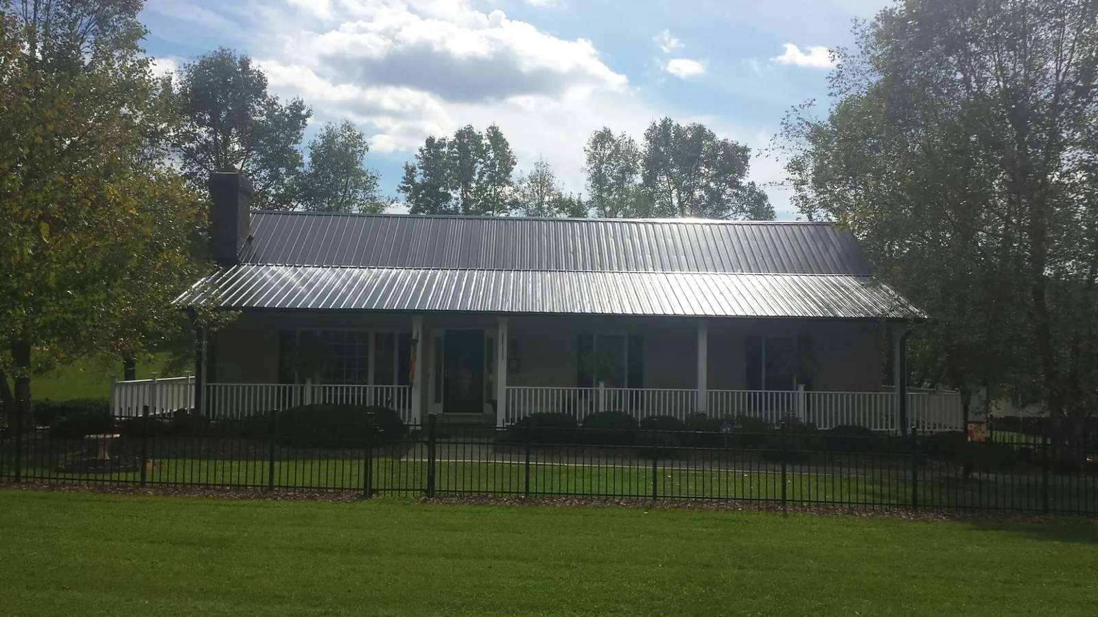 Gray metal roof on a brick ranch with a full width front porch — Gutter Guard Installation work by our crew in Rumney