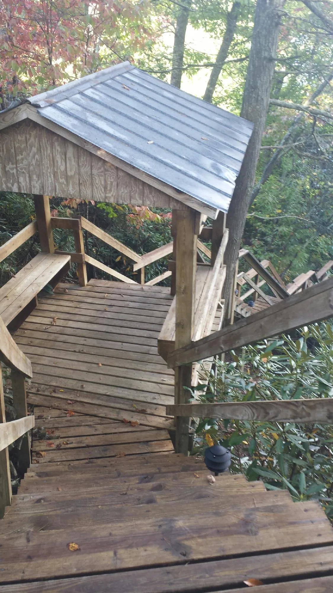 Metal roofed shelter over wooden steps on a wooded walkway — Skylight Repair & Installation work by our crew in Rumney