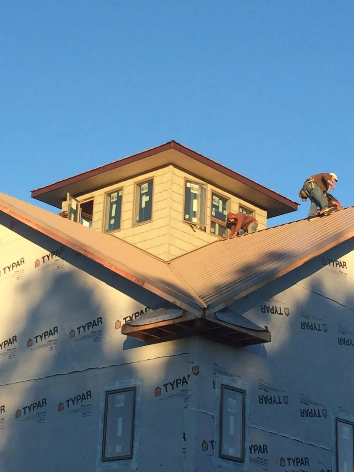 Roofers working around a rooftop cupola on a new metal roof at sunset — Roof Waterproofing in Rumney by Roofing Brothers